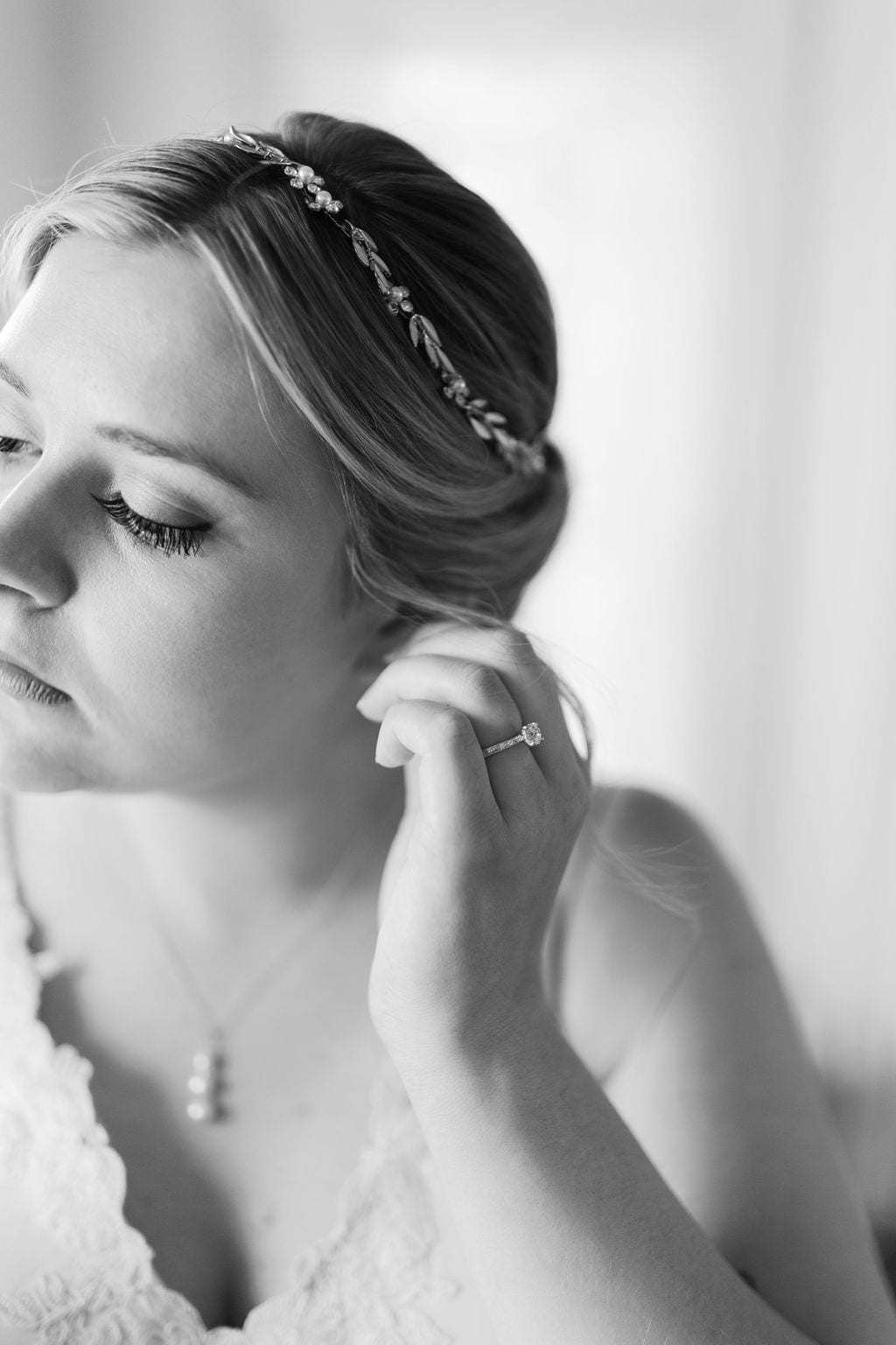 Grace and Miles wedding at Eldredge Manor, the bride fastens an earring, black and white