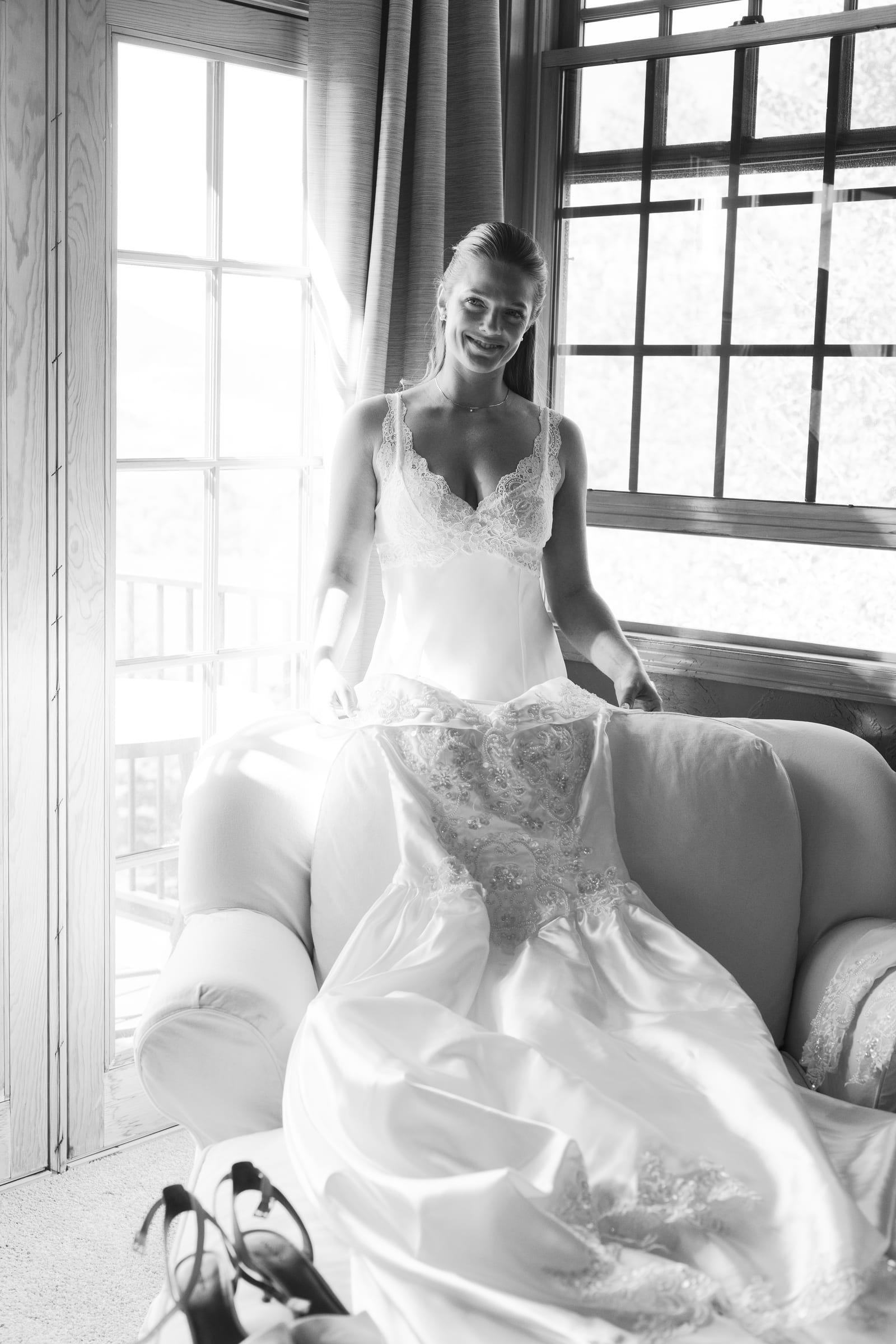 The wedding dress hanging in the window light, a Bellissimo Gardens wedding in Utah