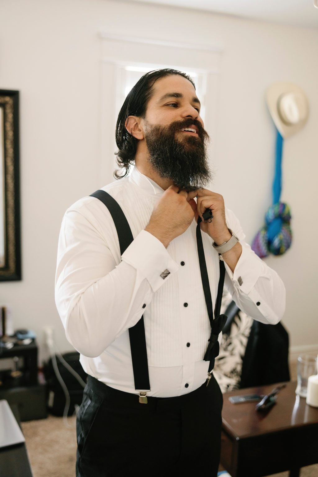 The groom getting ready in his shirt and suspenders before the ceremony, a Utah wedding morning