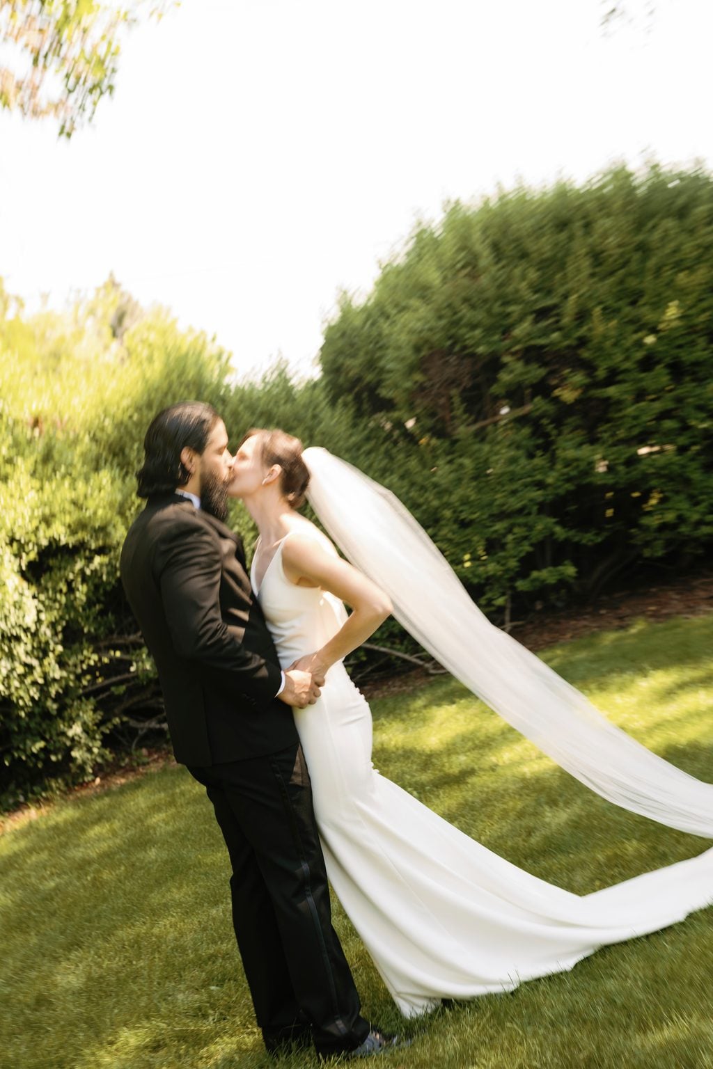 The groom holds the bride close, foreheads together beneath her veil in the garden, a Utah wedding