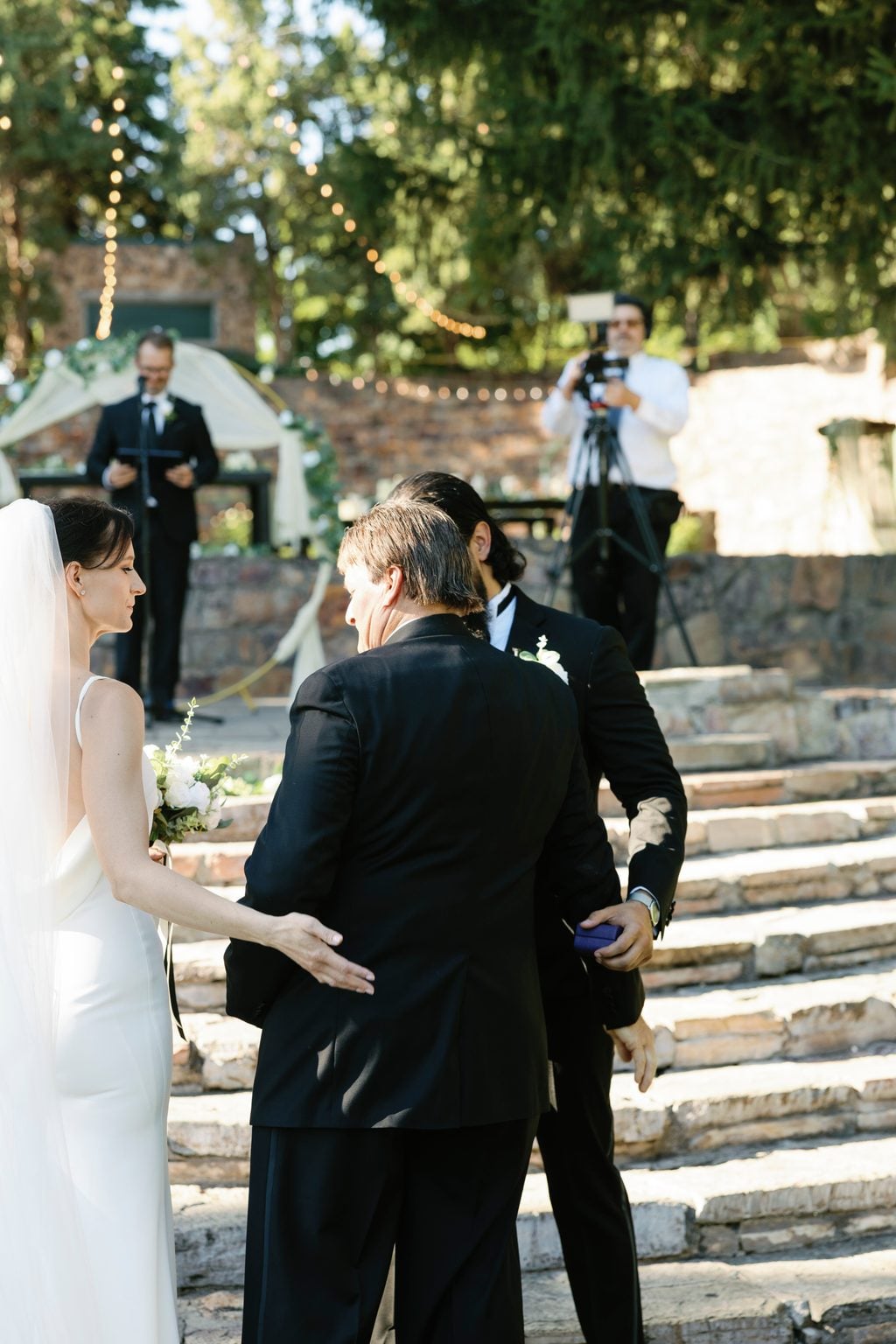 Mallory and Saint exchanging vows on the stone terrace under string lights