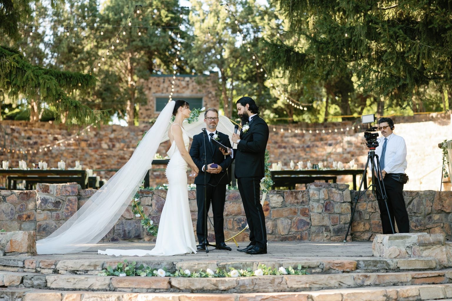 A young ring bearer walking the aisle as the bride's veil trails behind
