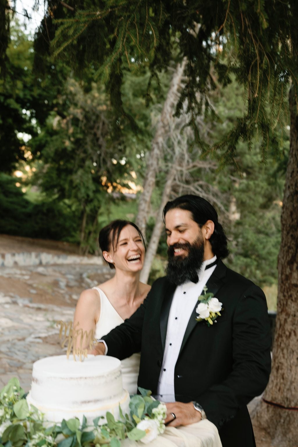 The naked cake dressed with greenery on a draped table at the garden reception