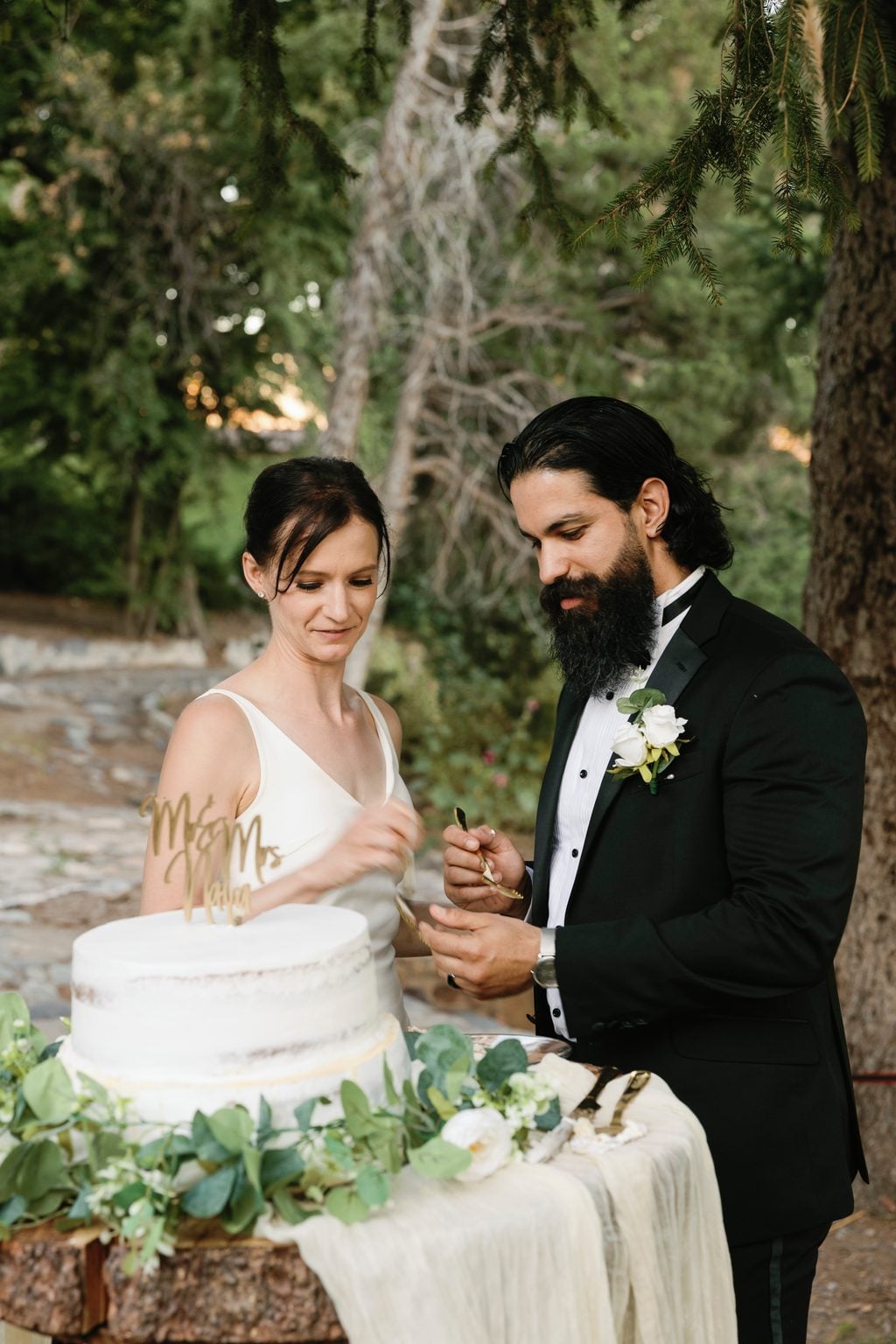 The couple sharing the first slice of cake at their garden reception