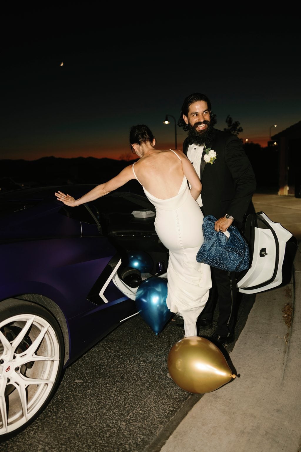 The couple's getaway at dusk, reaching for a waiting car as the mountains glow