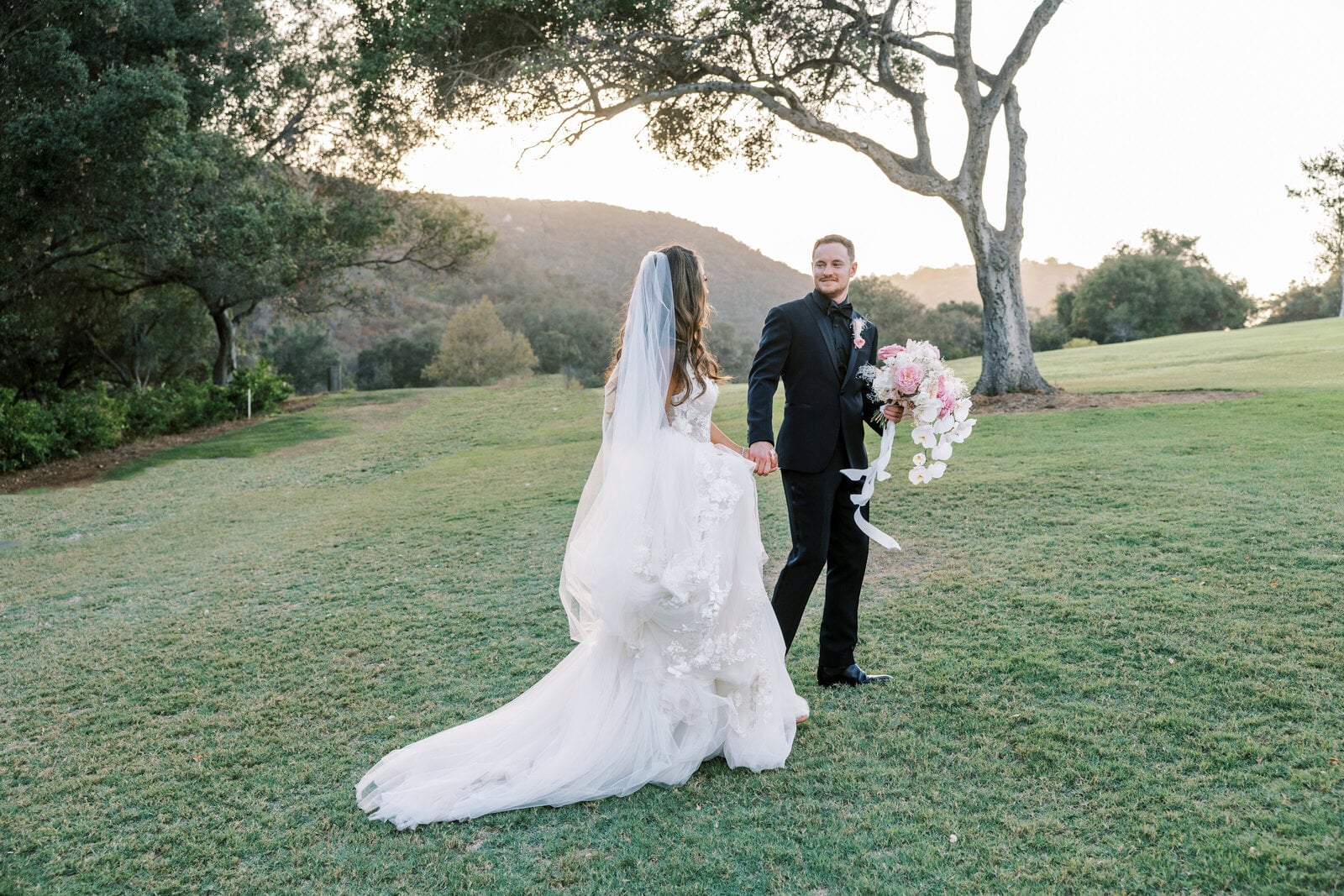 Chase and Ariana walk a golden field at last light, a Utah wedding