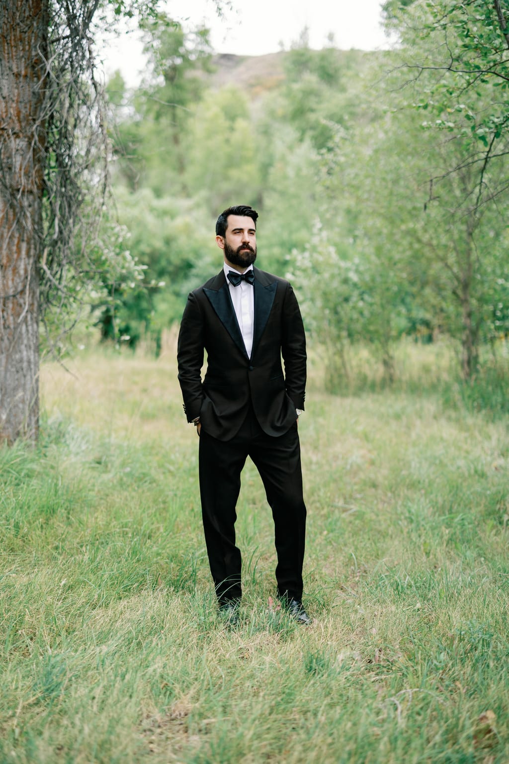 The groom in the meadow framed by trees and mountains, 4U Ranch wedding in Park City, Utah