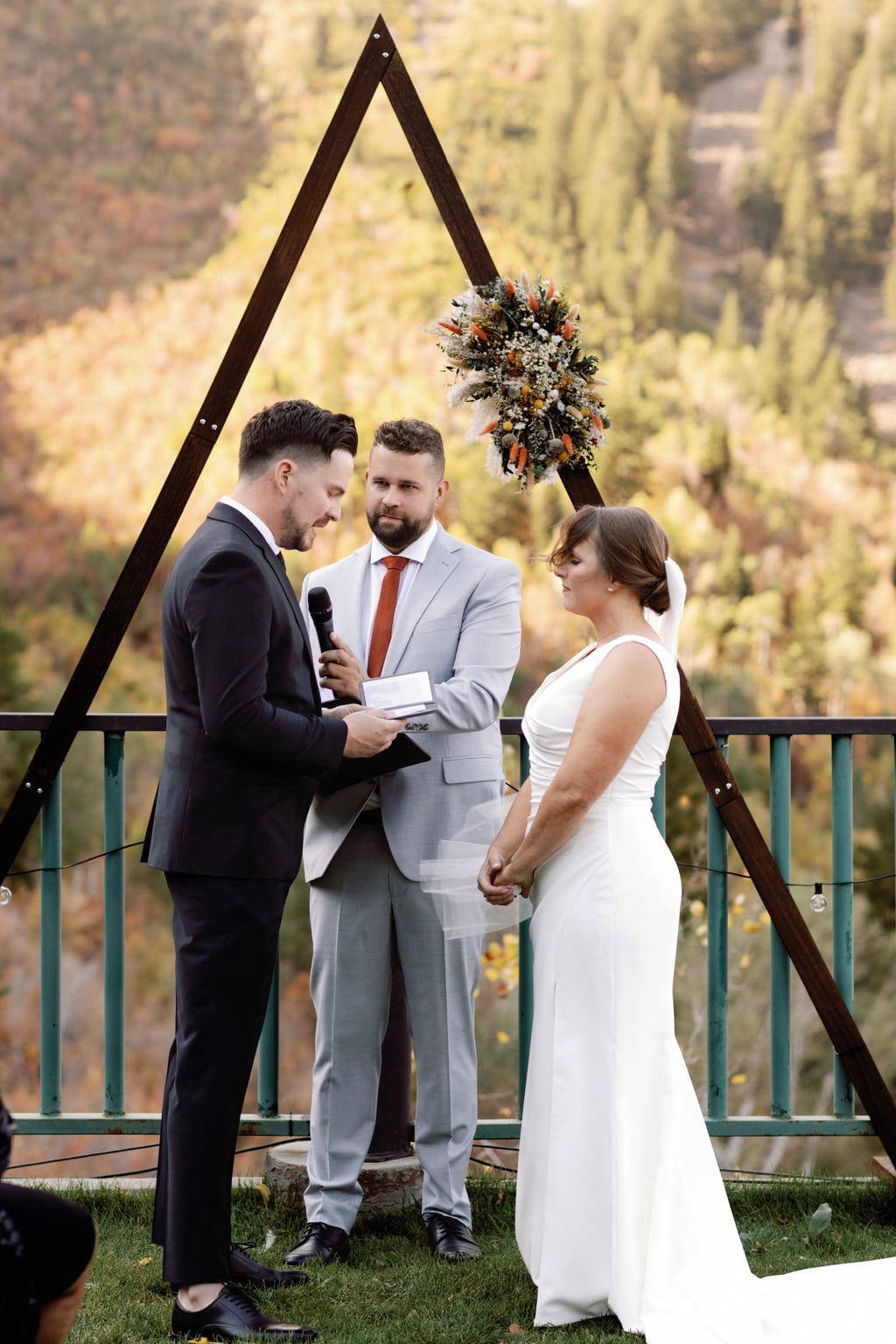 Wedding vows beneath a timber arch with the fall mountainside behind, a private residence in Sundance, Utah