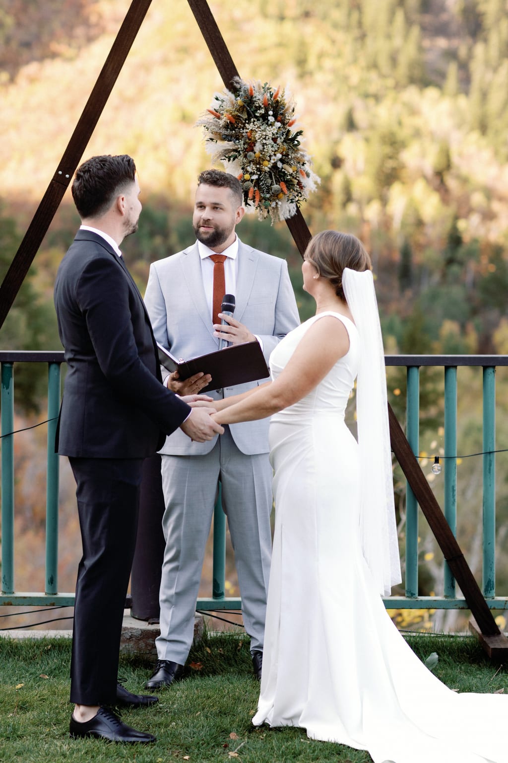 The couple at the arch with their officiant during the ceremony, private Sundance residence